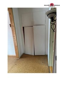 Fotografi av en innendørs romdeling med hvite skap og gulvbelegg.