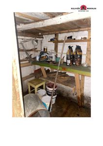 Fotografi av et lite, utilpasset rom (kanskje kjeller eller garasje) med arbeidsbenk og diverse verktøy.