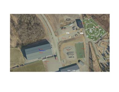 Flyfoto eller satellittbilde av et område med flere bygninger, vei og terreng, med overlagte målelinjer og tekstmerking.