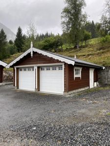 Fotografi av en ferdig bygget garasje med to dører og etasjefasade, sett fra et lavt vinkel.