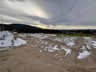 Fotografi av et tomt terreng med snøflekker, sannsynligvis en byggeplass eller et område som er forberedt for bygging.