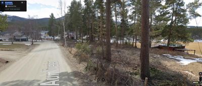 Fotografi av en vei (Aurnveien) og et naturområde med skog og fjell i bakgrunnen.