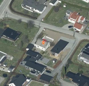 Flyfoto eller satellittbilde av et boligområde med en markert tomt og bygning.