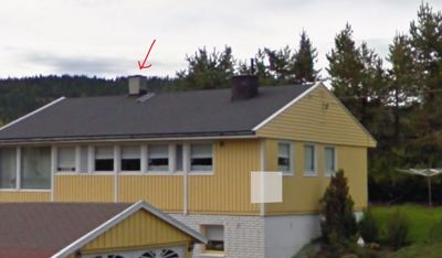 Fotografi av en gul villa sett fra siden, med fokus på fasaden og taket.