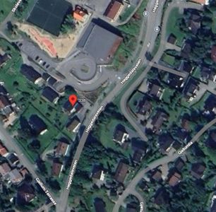Satellittbilde (flyfoto) av et boligområde med veinavn og en markør for eiendommen.