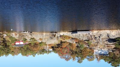 Fotografi av en kystlinje med hus, båtplasser og vann.