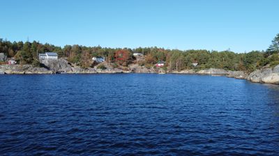 Fotografi av en kystlinje med flere hus plassert på en klipperik bakke. Bildet viser et eksisterende landskap og bygningsplassering.