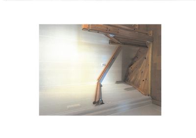 Fotografi av en innvendig hjørnekonstruksjon i en bygning, der det er synlig hvordan et tak eller etasjeskille er festet mot en vegg med trevirke.