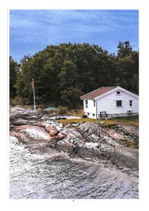 Fotografi av en hvit hytte på en steinete kyststrand med skog i bakgrunnen.