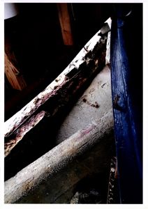 Fotografi av en konstruksjon, sannsynligvis en takkonstruksjon eller et takrom, som viser en betongbjelke eller takplate med synlig rust og skade.