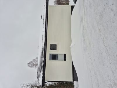 Fotografi av en bygning sett fra siden, med snø på taket og bakken.