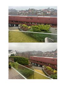 Fotografi av en rød bygning sett fra et balkongterrasse, med utsikt over nabolag og fjord.