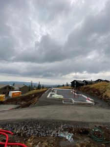 Fotografi av en byggeplass som viser fundamentet til en ny bygning under oppføring, med nabolag i bakgrunnen.