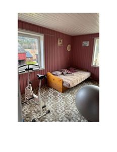 Fotografi av et innendørs rom (sannsynligvis et soverom eller etasje) med rød panelvegg, hvit takpanel, en sengeramme, en sykle, en ball og utsikt gjennom vinduet.