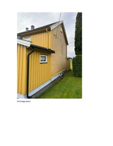 Fotografi av en gulfarget, trepanelt bygning sett fra siden (Nordveggen).