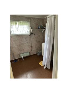 Fotografi av et bad eller toalettrom med flisvegger, dusjkurtegg, radiator og vindu.