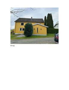 Fotografi av en gul bygning sett fra øst (Østvegg), med bil og trær i forgrunnen.
