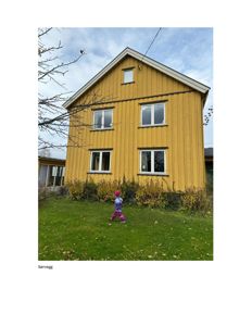 Fotografi av en gul, toetasjes bygning sett fra foran. Bildet viser fasaden, vinduer, tak og omgivelser med en person i forgrunnen.