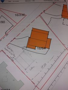 Situasjonsplan som viser tomtens form, grenser (røde linjer), nabotomter, eksisterende bygninger (grønn farge) og en planlagt bygning (oransje farge) med mål og avstander.