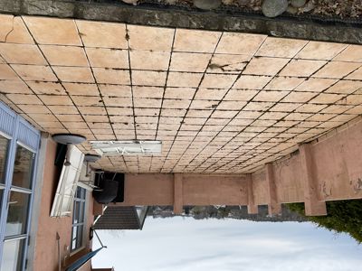 Fotografi av en terrasse eller balkong med flislagt gulv, en hvit sofa og en dør. Bildet er rotert 90 grader mot klokken.