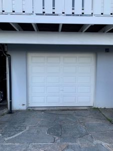 Fotografi av en hvit garasjeport med en steinlagt fortau foran.