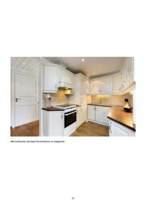 Fotografi av en kjøkkeninnredning med hvite skap, integrerte hvitevarer og tregulv.