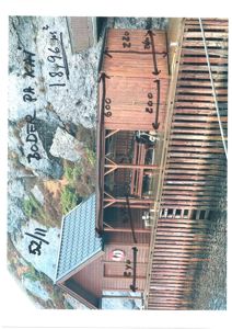 Fotografi av en eksisterende bygning (tømmerhus) med håndskrevne mål og areal beregnet på bildet.