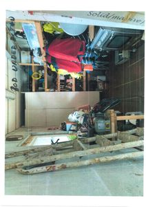 Fotografi av et innvendig rom (kanskje bod eller garasje) som er fullt av gjenstander, møbler og verktøy.