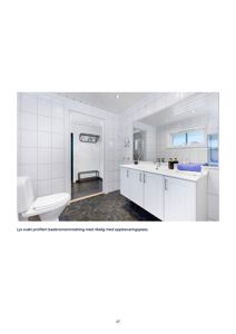 Fotografi av en innredet badromsinnredning med hvite fliser, toalett og vask.