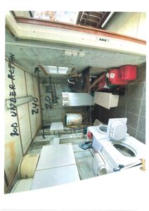 Fotografi av et innvendig rom (kanskje bad eller vaskerom) med håndskrevne mål og notater på veggen.