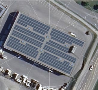 Luftfoto av et bygg med solcellepaneler på taket, sett fra oven.