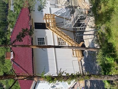 Fotografi av en bygning under ombygging eller utvidelse, med en ny trapp og fasade.