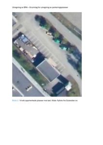 Flyfoto av et område med parkeringsplasser og bygninger.