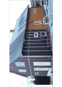 Fotografi av en bygning under oppføring eller renovering, med synlig fasadebehandling og tak.