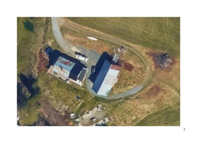 Luftfoto (satellittbilde) av to bygninger på en tomt med vei og omgivende terreng.
