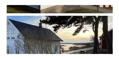 Fotografi av en hvit villa med tak og en rød bygning i bakgrunnen, sett fra et høyere nivå mot havet.