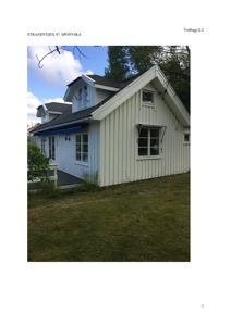 Fotografi av en hvit trehus med skrå tak og en liten veranda, sett fra siden.