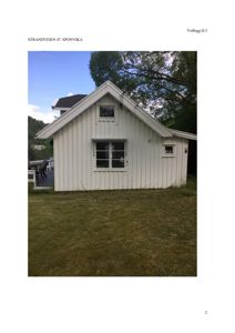 Fotografi av en hvit hytte med skrå tak sett fra bakkenivå.