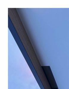 Fotografi av en bygningens fasade eller takkant sett fra nede mot himmelen.