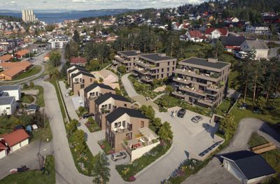 Fotografi av et boligfelt med moderne hus og leilighetsbygg, sett fra luften.