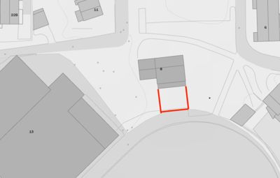 Situasjonsplan som viser tomt med bygninger (merket med tall) og omgivende infrastruktur. En rød rektangel markerer en spesifikk del av tomten eller en planlagt inngrep.