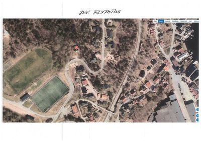 Flyfoto eller kartutsnitt som viser et nabolag med hus, veier og et idrettsanlegg.