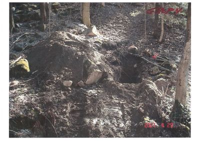 Fotografi av en utgravd jordhule eller grøft i skog.