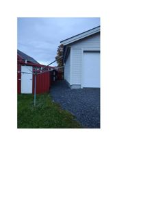 Fotografi av en uteplass med en hvit garasje, en rød uthusbygning og et trelasttørreanlegg.