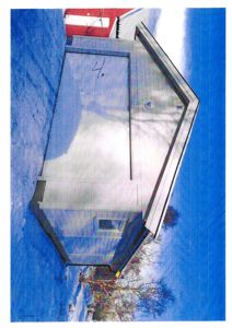 Fotografi av en liten, hvit bygning (kanskje uthus eller garasje) med et skråtak, sett fra siden.