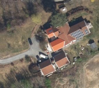 Luftfoto eller satellittbilde av en eiendom med flere bygninger, veier og omgivelser.