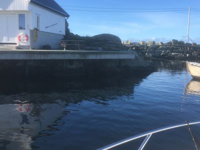 Fotografi av en hvit bygning ved vannet, sett fra en båt.