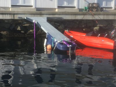 Fotografi av en brygge med en båt og en båttrailer i vannet.