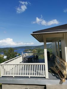 Fotografi av en terrasse med utsikt over vann og øyer, med deler av en bygning i forgrunnen.
