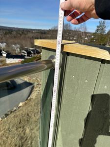 Fotografi av en person som måler høyden på en balustrade med en målebånd.